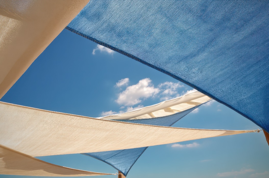 Moderne Terrasse im Sommer mit eleganten Sonnensegeln unter strahlend blauem Himmel